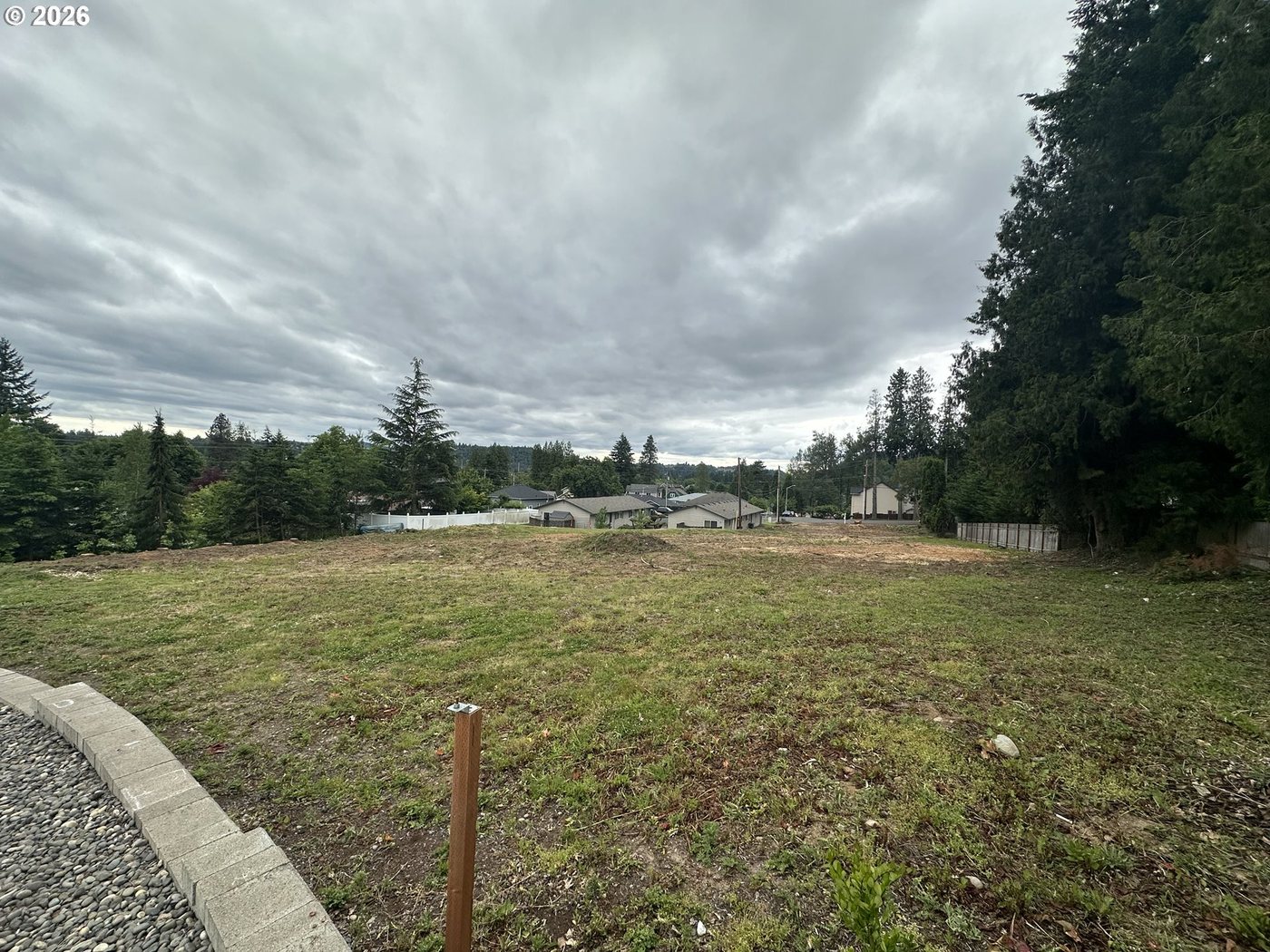 The lot at the curb line, with a survey marker in the foreground.